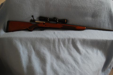 1991 Ford Bronco - Rifle with wooden stock and scope is displayed on a blue cloth background.