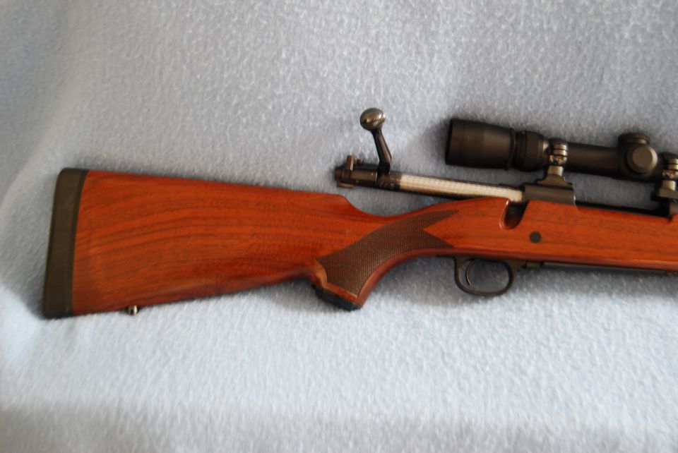 Bolt-action rifle with wooden stock and scope mounted on top