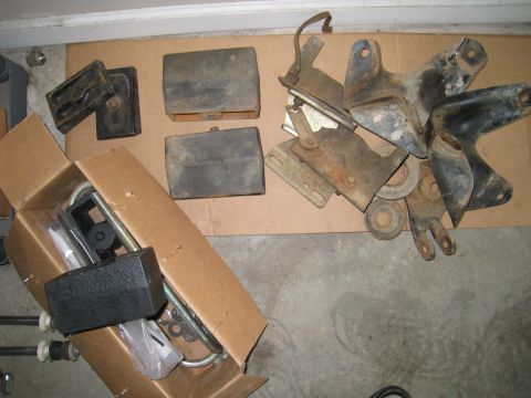 1996 Ford Bronco - Assorted vehicle parts, including brackets and rubber blocks, are laid out on a cardboard surface.