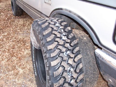 1990 Ford C-150 (Centurion Conversions) - A close-up of a large off-road tire mounted on a truck, with a "F150 CLASSIC" badge visible on the vehicle's body.