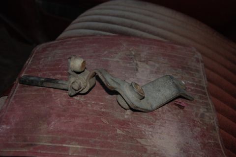 1987 Ford F-250 - Close-up of a metal transfer case shifter linkage component resting on a red surface.