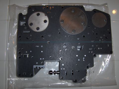 2004 Ford Crown Victoria - This is a valve body plate, likely for a transmission, shown in plastic packaging.
