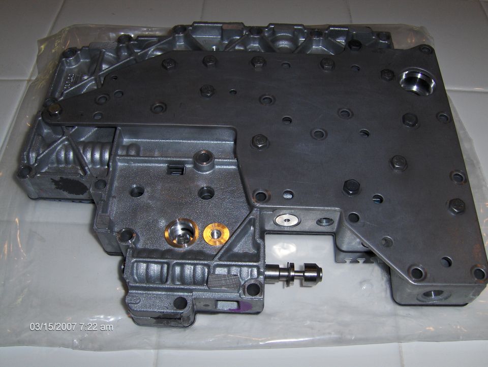 Metal valve body with various bolts and ports, some brass fittings visible