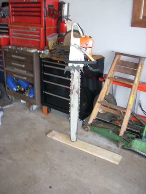 2000 Chevrolet Tahoe - A chainsaw is positioned vertically on a plank in a garage setting with tool chests and a ladder.