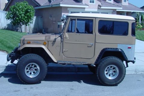 1992 Ford Bronco - This Toyota Land Cruiser FJ40 features a tan exterior and a white hardtop, seen from the side.