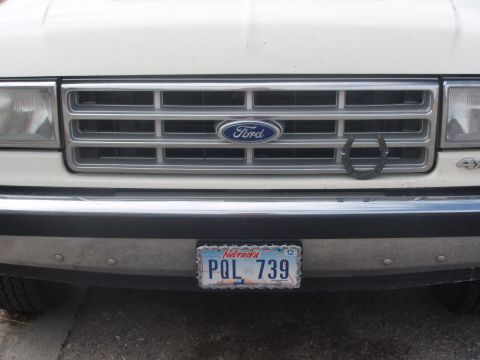 1987 Ford Bronco - Front view of a 1987 Ford Bronco, its grille, Ford emblem, and a horseshoe accessory.