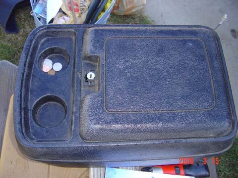 1983 Ford Bronco - This black center console features two cup holders and a lockable compartment, likely from an older vehicle.