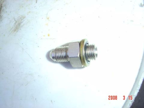 1983 Ford Bronco - Close-up of a metal fitting with threads and a nut, likely a plumbing or automotive part.