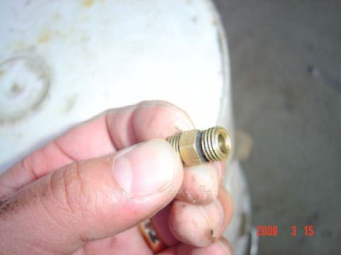 1983 Ford Bronco - A close-up shows a brass fitting with threaded ends and a black O-ring, held by a person's fingers.