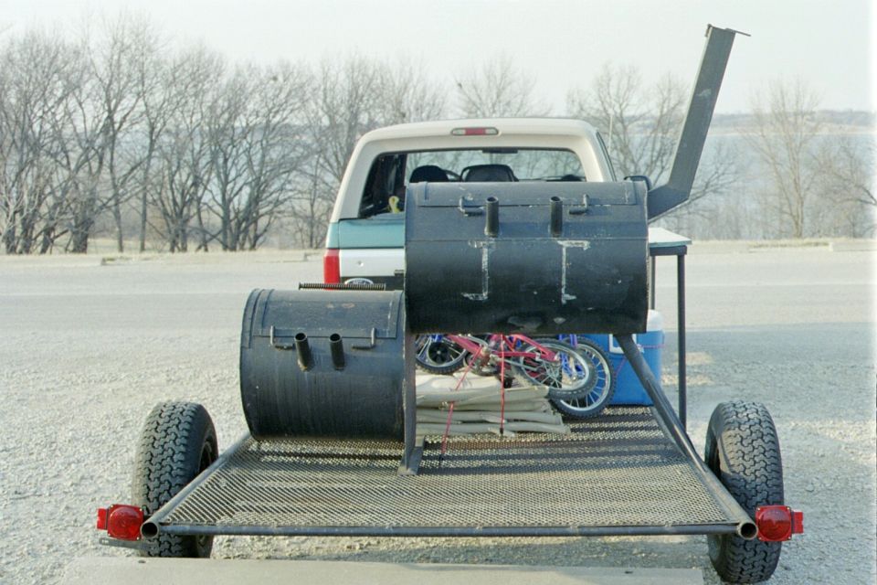 Trailer loaded with a large smoker and a child's bicycle, towed by an SUV