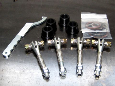 1996 Ford Bronco - A collection of aftermarket automotive suspension components, including adjustable control arms and bushings, are displayed on a workbench.