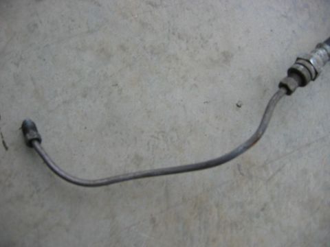 1985 Ford LTD Crown Victoria - A single metal brake line is shown against a concrete background.