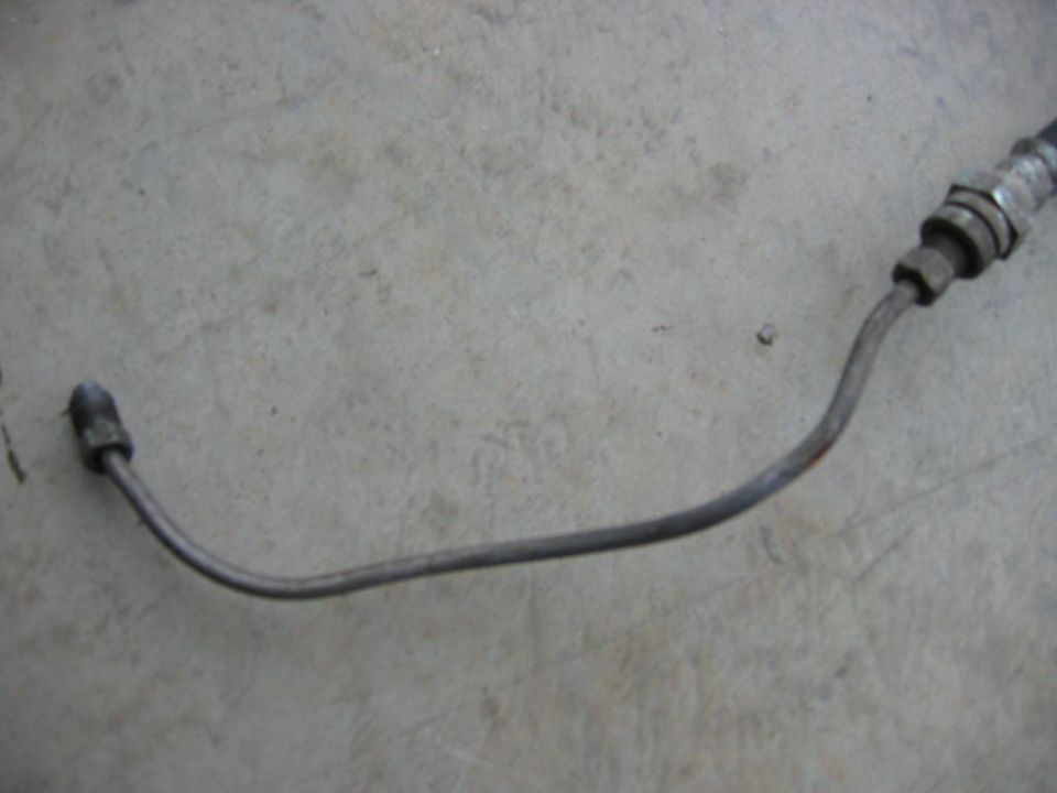 Metal brake line with fittings on a concrete surface