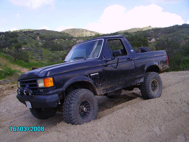 Black Ford Bronco on a dirt hill, lifted with large tires