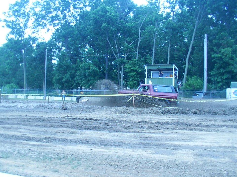 red SUV driving through mud pit