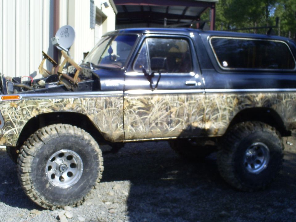 Black Ford Bronco with camouflage body wrap, lifted suspension, and off-road tires