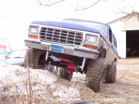 1978 Ford Bronco - This lifted Ford Bronco is shown off-road, with its front end angled upwards on a dirt embankment.