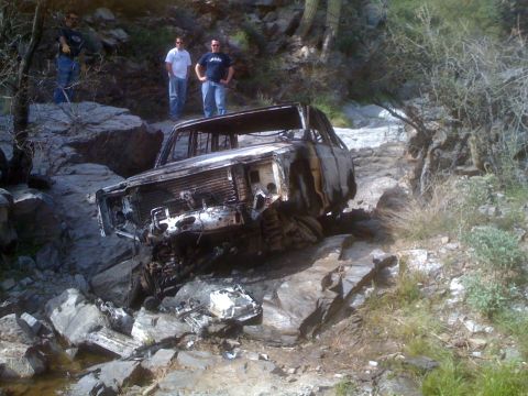 1966 Ford Bronco - A severely damaged 1966 Ford Bronco sits abandoned on a rocky, off-road path.