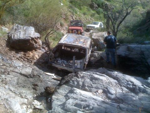1966 Ford Bronco - Multiple off-road vehicles navigate difficult rocky terrain, with one vehicle heavily damaged.