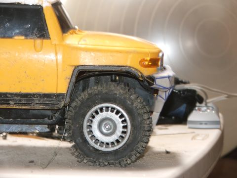 1996 Ford Bronco - Close-up of a yellow RC car's front wheel and modified bumper.