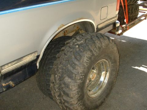 1991 Ford Bronco - The rear wheel well and tire of a 1991 Ford Bronco are visible, showing some rust around the wheel arch.