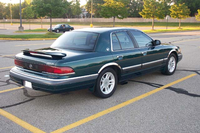 Green Mercury Grand Marquis rear three-quarter with deck spoiler in a parking lot