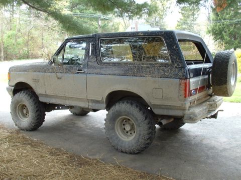1991 Ford Bronco - This heavily muddied Ford Bronco is viewed from its rear three-quarter angle, showing its off-road modifications.