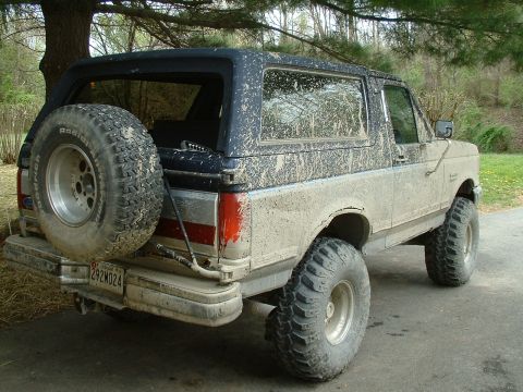 1991 Ford Bronco - Mud-splattered 1991 Ford Bronco seen from the rear with its spare tire mounted.