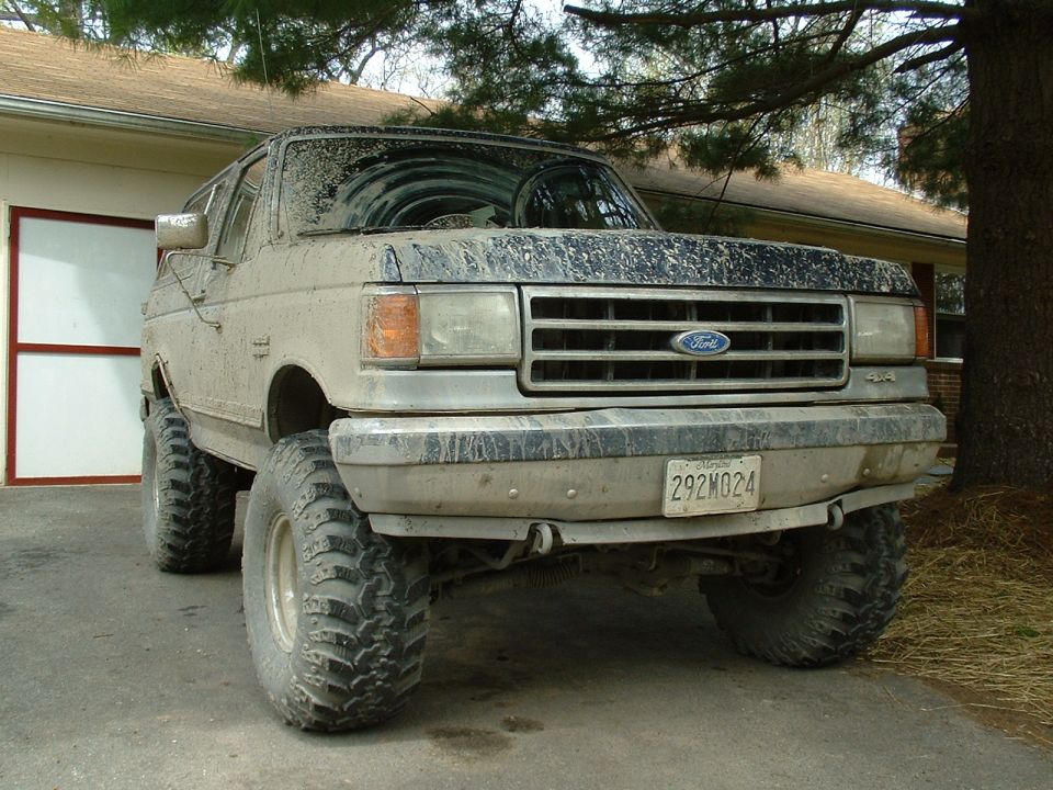 Mud-covered 1992 Ford Bronco with lifted suspension and off-road tires, front view