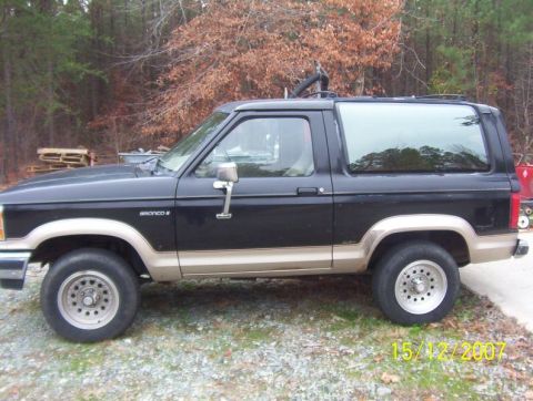 1988 Ford Bronco - Side profile of a 1988 Ford Bronco with two-tone paint and aftermarket wheels.