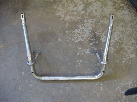1996 Ford Bronco - Bare-metal tubular roll bar hoop lying on a concrete garage floor after being stripped and welded, with flattened drilled mounting tabs at…