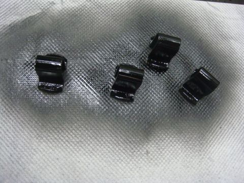 1996 Ford Bronco - Four small black-oxide metal clips or retainers laid out on a white shop towel, each a stamped and folded piece with a curved saddle and a…