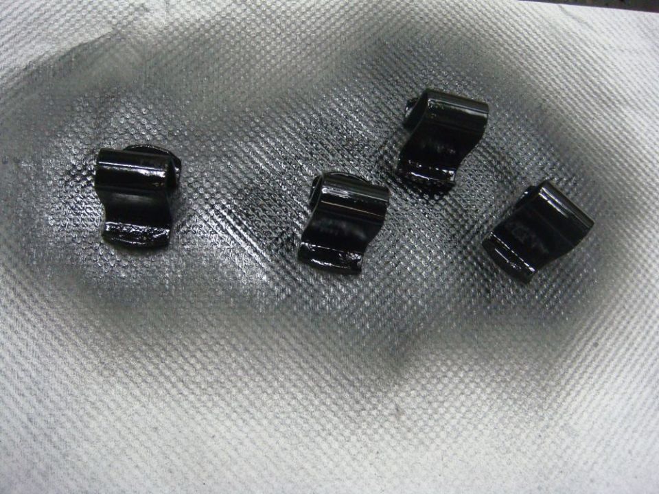 Four small black metal clips or retainers laid out on a white shop towel