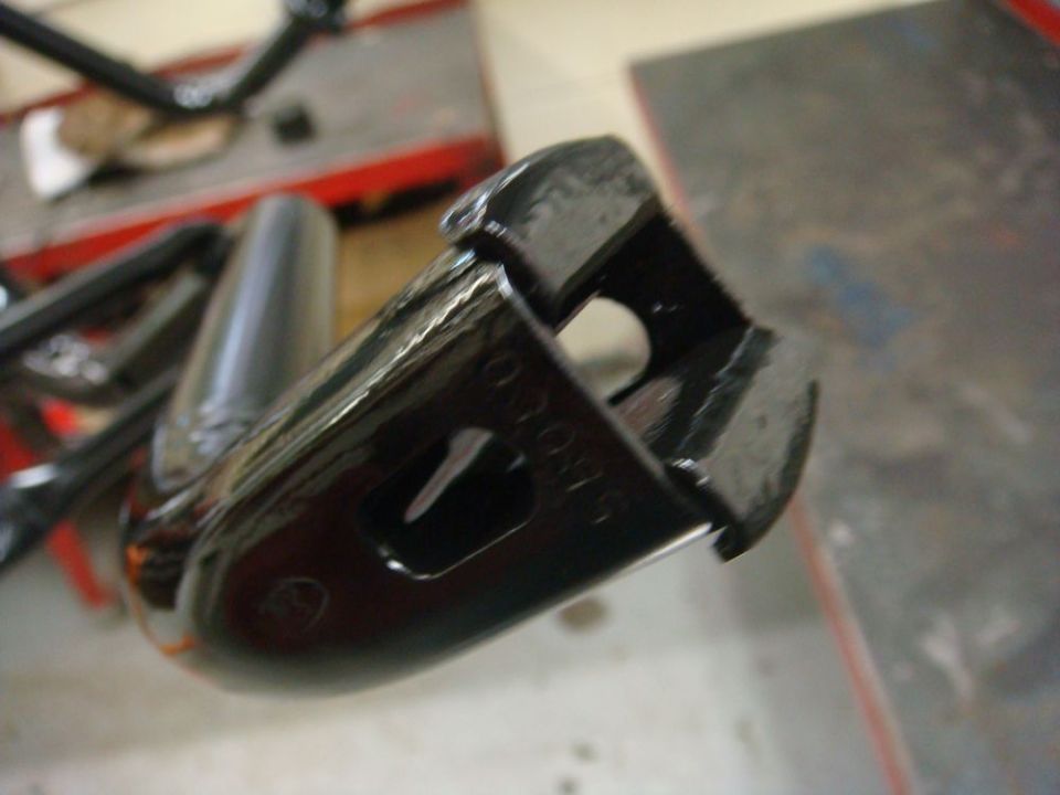 Glossy black freshly painted steel bracket with cast number held in a shop