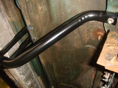 1996 Ford Bronco - Underbody detail of a freshly painted black tubular bar, a nerf/rock-slider or side step tube, bolted through brackets to the rocker pinch…