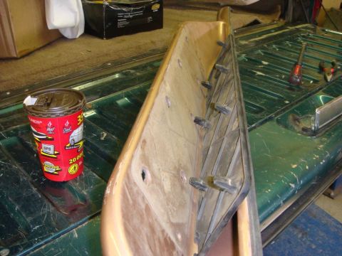1996 Ford Bronco - A tan interior trim panel stood on edge shows its backside with molded studs and a bare metal reinforcement bracket, resting on a scratched…