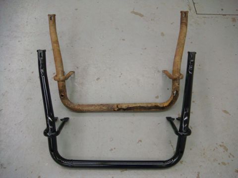 1996 Ford Bronco - Two tubular truck brackets laid side by side on a concrete shop floor for comparison: the upper one heavily rusted and pitted with flaking…