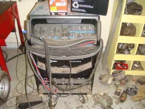 1996 Ford Bronco - Miller welder and a collection of car parts, including alternators, are stored in a workshop.