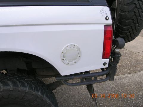 1996 Ford Bronco - Close-up of the rear of a white SUV, showing the fuel door and part of the spare tire assembly.