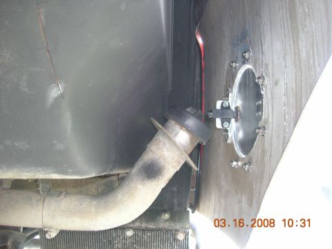 1996 Ford Bronco - Close-up view of a vehicle's fuel filler neck and a circular access panel on the underside.