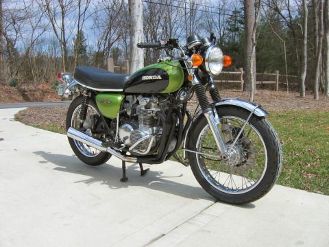1985 Ford Crown Victoria LTD - A two-tone green and black Honda motorcycle is parked on a concrete surface with trees in the background.