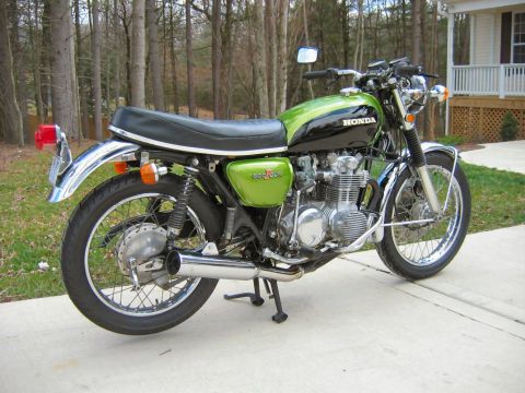 1985 Ford Crown Victoria LTD - A green and black Honda motorcycle is parked on a concrete driveway with trees in the background.
