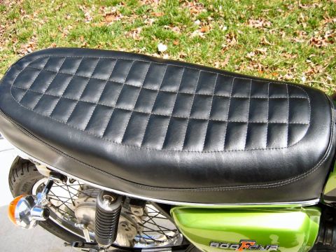 1985 Ford Crown Victoria LTD - A close-up of a black diamond-stitched seat on a green motorcycle, with visible text indicating '600Four'.