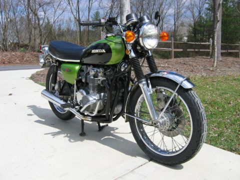 1985 Ford Crown Victoria LTD - A green and black Honda motorcycle is parked on a sidewalk with a wooden fence in the background.