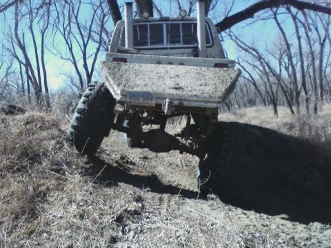 1992 Ford F-350 - This heavily modified pickup truck is navigating a muddy, wooded terrain.
