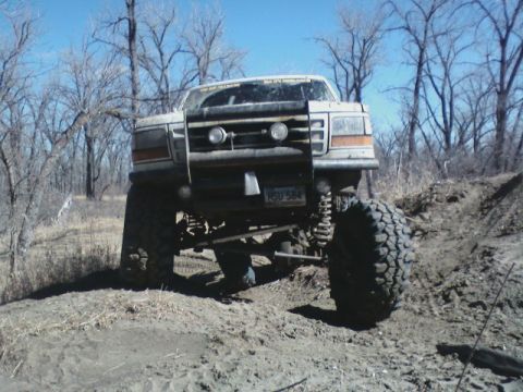 1992 Ford F-350 - A heavily modified 1992 Ford F-350 navigates an off-road trail with its large tires and lifted suspension.