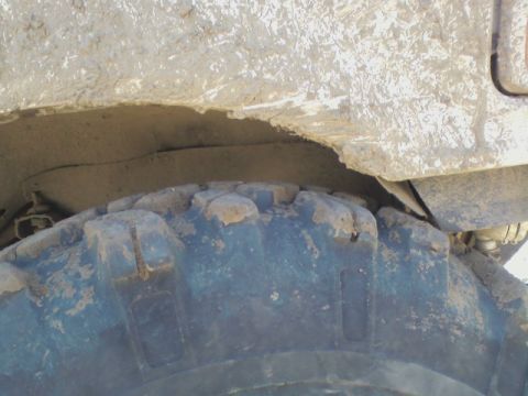 1992 Ford F-350 - Close-up view of a heavily muddied tire and the underside of a truck's fender well.