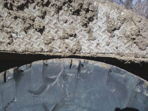1992 Ford F-350 - Close-up of a tire and mud-covered diamond plate, likely from an off-road vehicle.