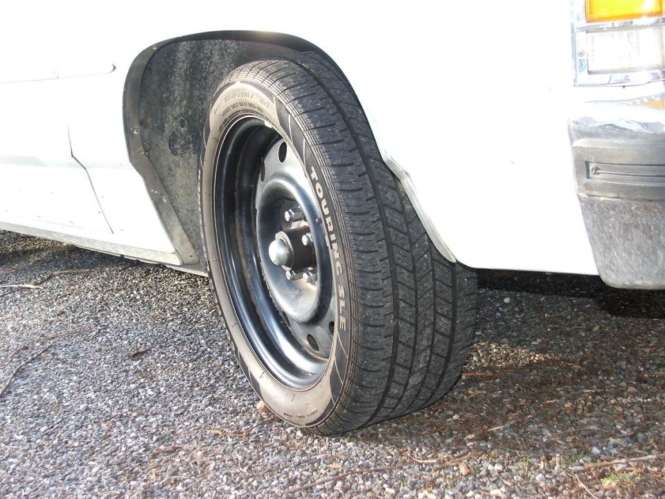 White car wheel with steel rim and "TOURING SLC" tire text