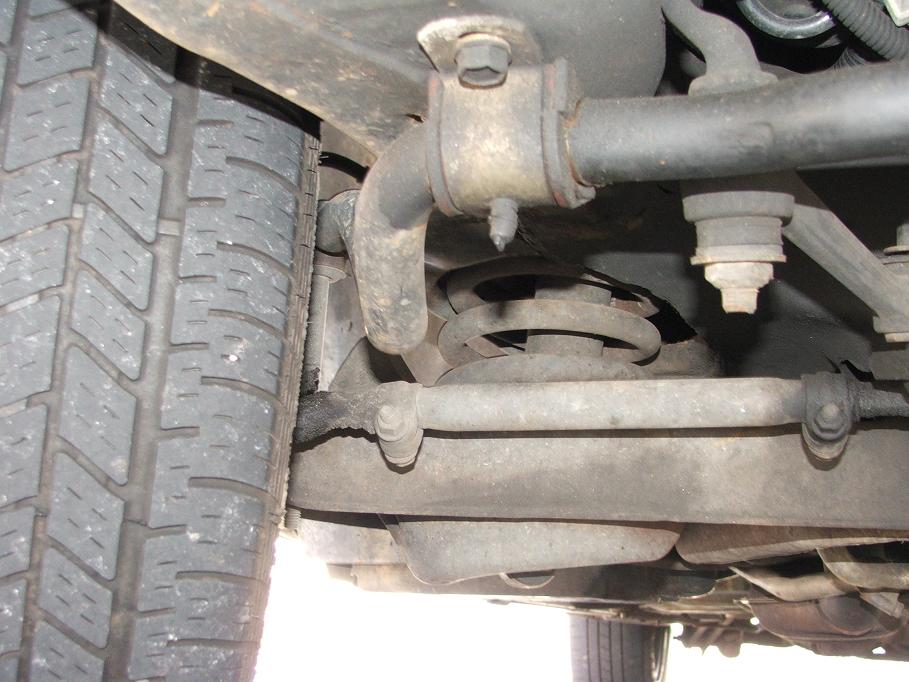 Undercarriage of a 1985 Ford Crown Victoria LTD showing suspension components and a steel wheel
